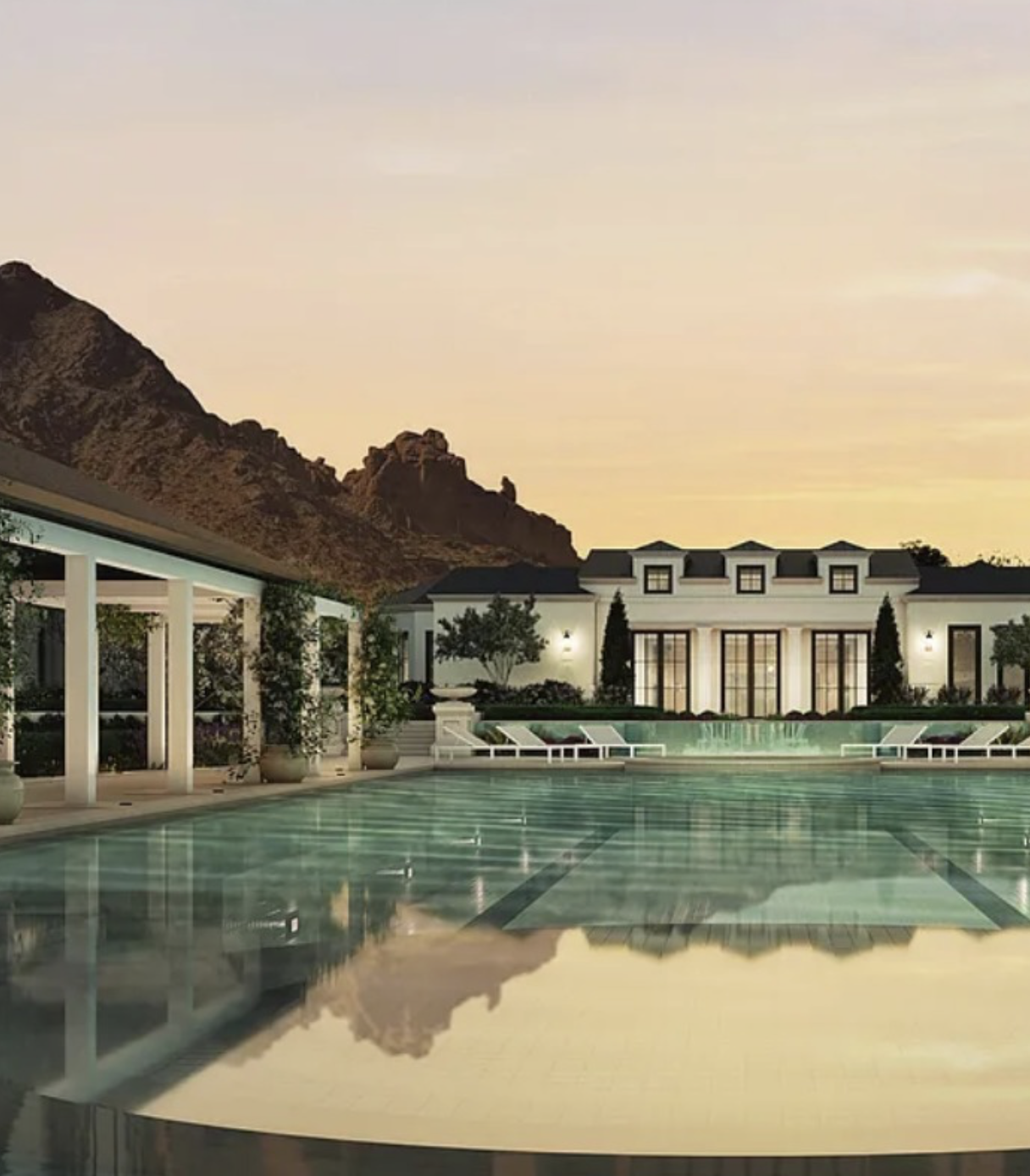 Luxury estate pool reflecting the residence at dusk.