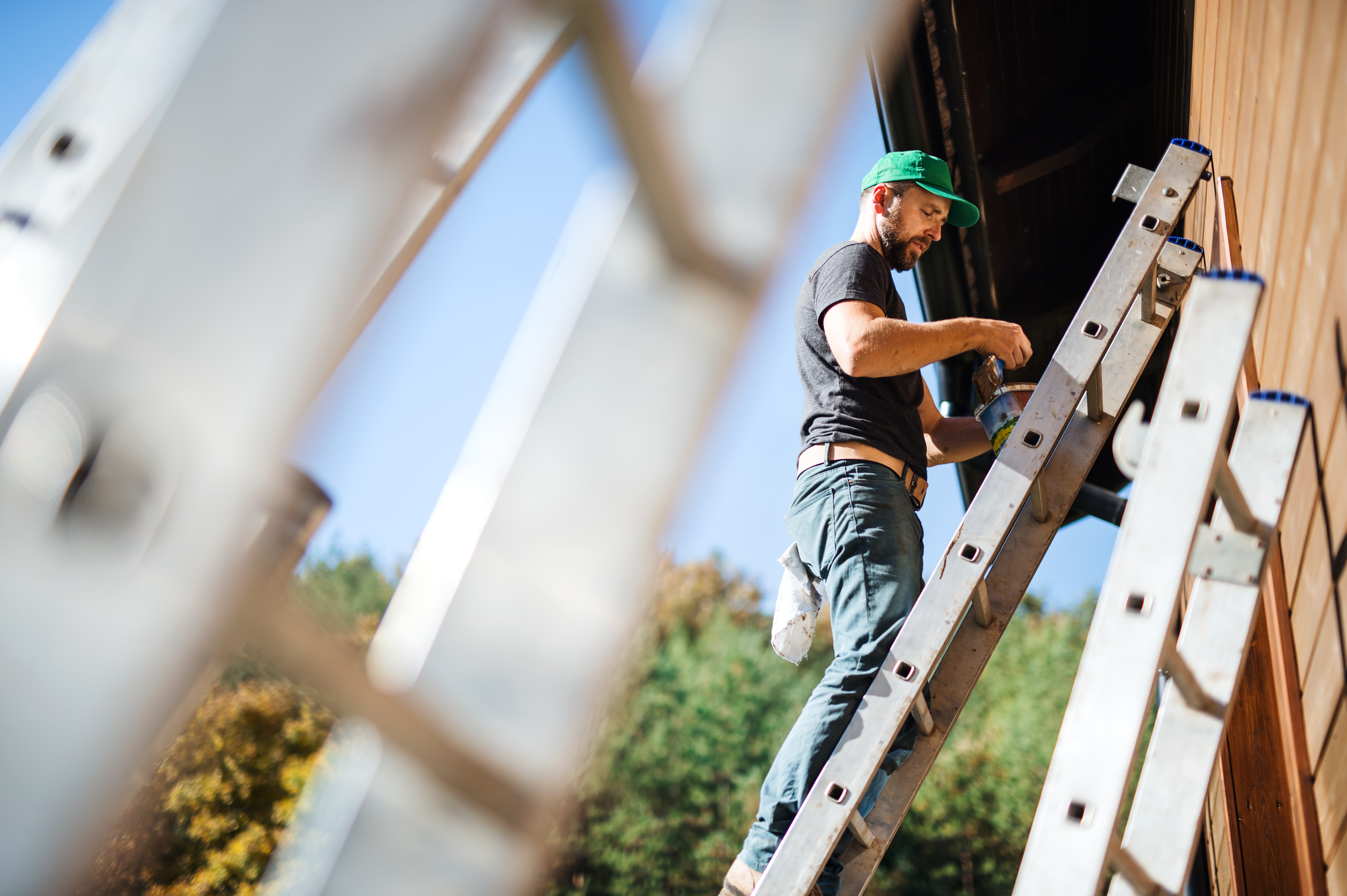 Maintenance worker on a ladder servicing an estate exterior.